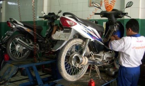 Salah seorang mekanik tengah memeriksa motor pelanggan.