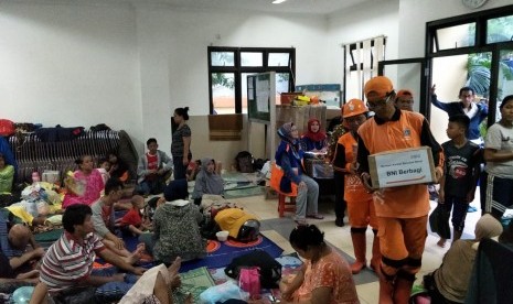 Salah seorang pegawai BNI sedang membagikan nasi bungkus pada warga yang terdampak bencana banjir di Jakarta, Rabu (1/1).