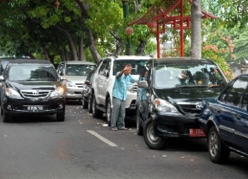 Salah seorang petugas parkir tengah mengatur kendaraan yang parkir.