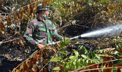 Salah seorang prajurit Kostrad memadamkan kebakaran hutan