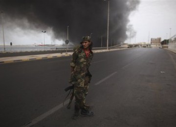 Salah seorang prajurit NTC berdiri di tengah jalan ketika gudang senjata milik pasukan Qadafi meledak di kawasan pelabuhan Tripoli, Libya, Sabtu (24/9).