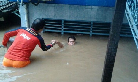 Salah seorang relawan tengah mengevakuasi korban banjir