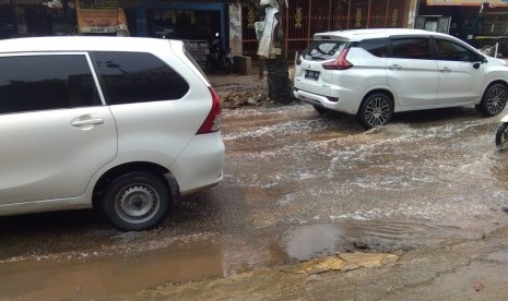 Saluran air tersumbat di Jalan Raya Parpostel,  Jatiasih,  Kota Bekasi mengakibatkan air selokan menggenang ke tengah jalan.