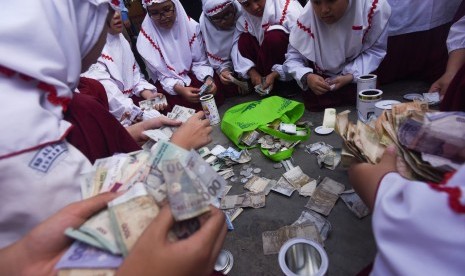 Sangu Lebaran Untuk Dhuafa. Sejumlah murid SD Al Falah Surabaya menghitung uang tabungan selama libur Lebaran ketika hari pertama masuk sekolah di halaman Sekolah mereka, Surabaya, Jawa Timur, Senin (27/7). 