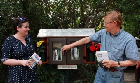 Sarah dan John memeriksa buku di Perpustakaan Mini Gratis miliknya. 