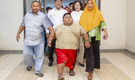 Satia Putra (7) penyandang obesitas dengan berat badan mencapai 101 kg didampingi Wakil Bupati Karawang Ahmad Zamaksyari (kedua kiri) bersama kedua orangtuanya berjalan menuju lokasi pemeriksaan medis di Rumah Sakit Umum Daerah (RSUD) Karawang, Karawang, Jawa Barat, Rabu (3/7/2019). 