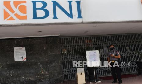 Satpam berjaga di depan Kantor Cabang BNI 46 yang ditutup sementara di Kota Madiun, Jawa Timur, Rabu (19/1/2022). Kantor Cabang BNI 46 Kota Madiun menutup sementara layanan hingga 20 Januari 2022 karena 10 karyawannya terpapar terpapar COVID-19.