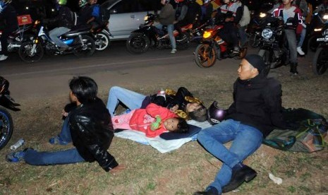  Satu keluarga pemudik beristirahat memanfaatkan alas seadanya untuk tidur sejenak saat berhenti di salah satu 