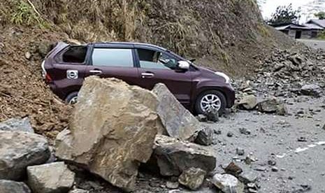 Satu unit mobil tertimbun material longsoran tanah dan batu di kawasan Kebun Kopi, kota Palu di Sulawesi Tengah, Sabtu (29/9).