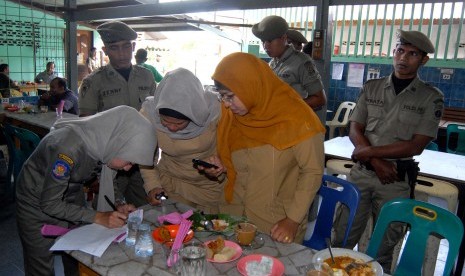 Satuan Polisi Pamong Praja (Satpol PP) mencatat identitas (KTP) dua orang PNS (kanan) yang terjaring saat razia disiplin di salah satu warung kopi. 