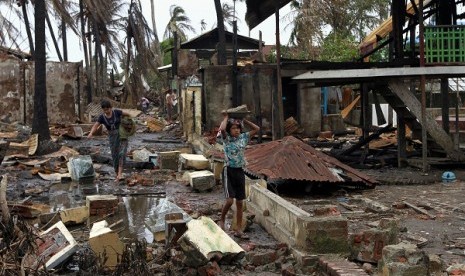 Saturday, June 16, 2012 file photo, a girl and a woman carry useable bricks from damaged buildings in Sittwe, capital of Rakhine state in western Myanmar. Communal violence is grinding on in western Myanmar six weeks after the government declared a state o