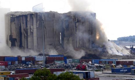 Sebagian dari silo yang rusak selama ledakan besar Agustus 2020 di pelabuhan runtuh dan menyebabkan asap dan debu ke udara di Beirut, Lebanon, Kamis, 4 Agustus 2022. Sebagian besar runtuh pada hari Kamis ketika ratusan orang berbaris di Beirut untuk menandai peringatan kedua ledakan yang menewaskan banyak orang.