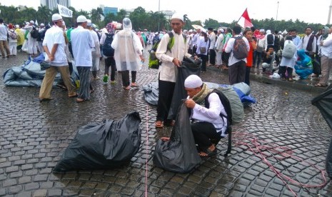 Sebagian massa melakukan pengumpulan sampah secara sukarela di Lapangan Monas, Jakarta usai melaksanakan shalat Jumat bersama, Jumat (2/12).