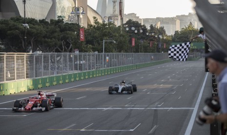 Sebastian Vettel melintasi garis finis GP Azerbaijan di depan Lewis Hamilton, pada Ahad (25/6).