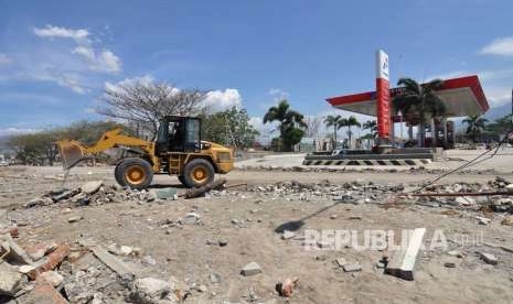 Sebuah alat berat membersihkan material sisa gempa dan tsunami yang menutupi badan jalan di Palu, Sulawesi Tengah, Jumat (5/10). 