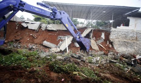 Sebuah alat berat mengangkut material longsor yang jatuh ke aliran Sungai Pesanggrahan, Raga Jaya, Bojonggede, Kabupaten Bogor, Jawa Barat, Selasa (9/2/2021). Longor disebabkan luapan sungai yang menggerus turap di bantaran sungai.