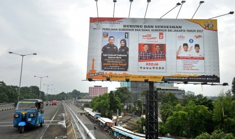 Sebuah angkutan umum melintas di dekat baliho sosialisasi Pilkada Gubernur dan Wakil Gubernur DKI Jakarta Tahun 2017 di Jakarta, Jumat (10/2).