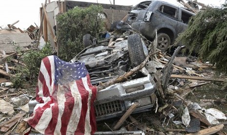 Sebuah bendera Amerika terletak di atas sebuah puing mobil yang hancur diterjang tornado di Moore, Oklahoma, Senin (20/5) waktu setempat.    