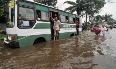 Sebuah bus Kopaja berusaha menerobos banjir di Jalan Daan Mogot, Jakarta Barat, Ahad (13/1). 