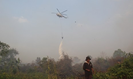 Sebuah helikopter melakukan pengeboman air (water bombing) terhadap lahan yang terbakar dekat permukiman warga di Kecamatan Dumai Timur, Kota Dumai, Riau, Kamis (7/3/2019).