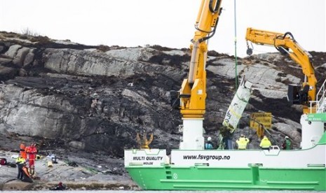 Sebuah kapal penyelamat mengangkat beberapa bagian helikopter yang jatuh di pulau Turoey dekat Bergen, Norwegia, Jumat, 29 April 2016. Sebanyak 13 orang tewas dalam insiden itu.