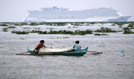  Sebuah kapal pesiar berlabuh di Teluk Manila menjelang tibanya Badai Tropis Molave, sementara nelayan setempat menangkap ikan, di Manila, Filipina, 25 Oktober 2020. Topan Molave melanda sebagian besar wilayah Filipina pada Senin (26/10).  