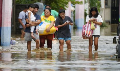 Sebuah keluarga mengungsi ke tempat yang lebih tinggi saat mereka mengarungi banjir dari Topan Noru di kota San Miguel, provinsi Bulacan, Filipina, Senin, 26 September 2022. Topan Noru bertiup dari Filipina utara pada hari Senin, menyebabkan beberapa orang tewas, menyebabkan banjir dan pemadaman listrik dan memaksa pejabat untuk menangguhkan kelas dan pekerjaan pemerintah di ibu kota dan provinsi-provinsi terpencil.