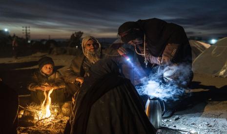 Sebuah keluarga menyiapkan teh di luar kantor Direktorat Bencana tempat mereka berkemah, di Herat, Afghanistan, Senin, 29 November 2021. Sekitar 2000 pengungsi meninggalkan desa Allahyar di provinsi Ghor karena kekeringan dan mencari bantuan dari daerah pemerintahan di Herat. Perubahan iklim menyebabkan kekeringan terparah di Afghanistan dalam beberapa dekade terakhir.