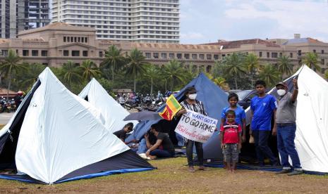 Sebuah keluarga Sri Lanka berdiri di luar tenda mereka di tempat para pengunjuk rasa berkemah di Kolombo, Sri Lanka, Rabu, 13 April 2022. Perdana Menteri Sri Lanka pada hari Rabu menawarkan untuk bertemu dengan para pengunjuk rasa yang menempati pintu masuk kantor presiden, mengatakan dia akan mendengarkan ide-ide mereka untuk menyelesaikan tantangan ekonomi, sosial dan politik yang dihadapi negara.