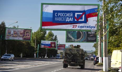 Sebuah kendaraan militer melaju di sepanjang jalan dengan papan iklan bertuliskan: Dengan Rusia selamanya, 27 September, sebelum referendum di Luhansk, Republik Rakyat Luhansk yang dikendalikan oleh separatis yang didukung Rusia, Ukraina timur, Kamis, 22 September 2022. Pemungutan suara dimulai Jumat di empat wilayah Ukraina yang dikuasai Moskow mengenai referendum untuk menjadi bagian dari Rusia.