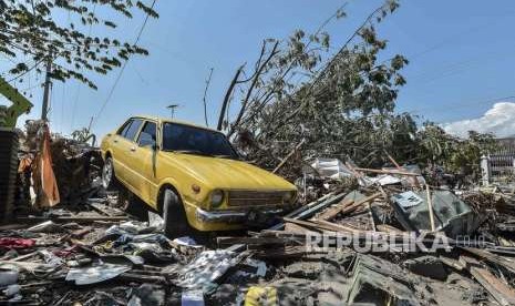 Sebuah mobil berada di reruntuhan bangunan yang hancur akibat tsunami pascagempa di wilayah Talise, Palu Barat, Sulawesi Tengah, Ahad (30/9).