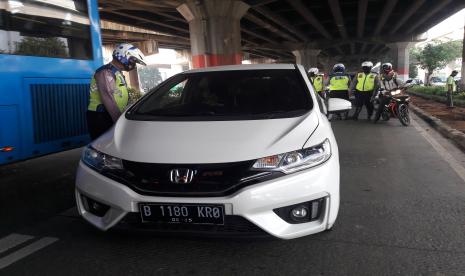 Sebuah mobil diberhentikan petugas polisi karena melanggar sistem ganjil genap yang mulai diberlakukan Senin (3/8). Penindakan terhadap pelanggar baru akan dilakukan mulai Kamis (6/8) mendatang.