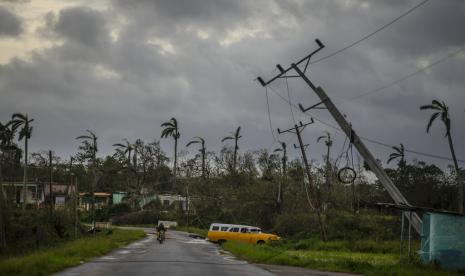 Sebuah mobil melewati tiang listrik yang miring akibat badai di AS (ilustrasi). Badai dan tornado yang melanda AS menyebabkan sedikitn ya 18 orang meninggal dunia. (ilustrasi).