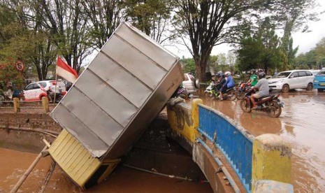 Sebuah mobil masuk ke sungai setelah terseret bajir di depan kantor Walikota Manado, Sulawesi Utara, Kamis (16/1).      (Antara/Fiqman Sunandar)