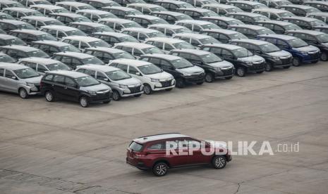 Sebuah mobil melintas di dekat mobil baru yang terparkir di PT Indonesia Terminal Kendaraan atau IPC Car Terminal, Cilincing, Jakarta. ilustrasi