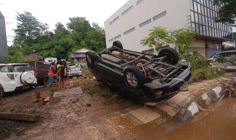  Sebuah mobil terbalik akibat terseret bajir di kawasan kantor Walikota Manado, Sulawesi Utara, Kamis (16/1).     (Antara/Fiqman Sunandar)