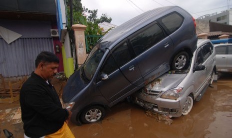  Sebuah mobil terbalik akibat terseret banjir di kawasan kantor Walikota Manado, Sulawesi Utara, Kamis (16/1).    (Antara/Fiqman Sunandar)