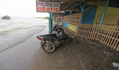 Sebuah motor terparkir di depan lapak pedagang yang sudah tidak ditempati akibat abrasi di pantai Karangsong, Indramayu, Jawa Barat, Selasa (14/6/2022). Abrasi pantai di objek wisata tersebut terjadi akibat banjir rob di beberapa pekan terakhir dan menyebabkan kerusakan bibir pantai dan kerusakan lapak milik pedagang. 