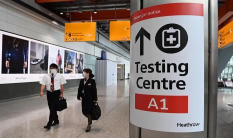 Sebuah papan petunjuk arah ke pusat tes Covid-19 terpasang di Bandara Heathrow di London, Inggris, 31 Juli 2021. Seorang dokter menduga pelonggaran lockdown dan kembali dibukanya perbatasan internasional mungkin telah membuka pintu untuk penularan infeksi baru, dalam hal ini cacar monyet. 