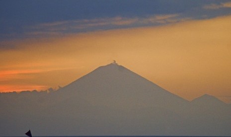 Sebuah perahu nelayan melintas dengan latar belakang Gunung Agung saat matahari terbenam di pantai Senggigi, Kecamatan Batulayar, Lombok Barat, NTB, Rabu (27/9). 