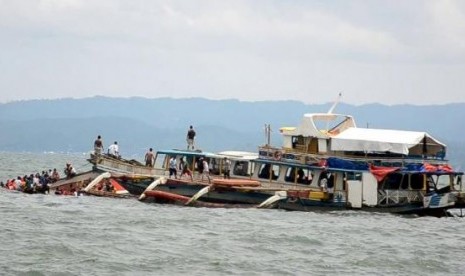 Sebuah perahu tongkang menyelamatkan penumpang kapal motor MBCA Kim-Nirvana (kiri) yang tenggelam setelah meninggalkan pelabuhan Ormoc City, Manila, Filipina, Kamis (2/7).