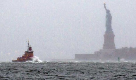 Sebuah perahu tug melintasi deburan ombak dekat Patung Liberty di New York, Senin (29/10) waktu setempat.     (Craig Ruttle/AP)  