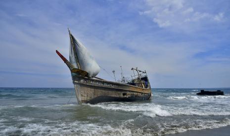 Sebuah perahu yang digunakan untuk mengangkut etnis Rohingya terdampar di pantai Indra Patra di desa Ladong, provinsi Aceh, Indonesia,  Ahad, (25/12/2022).. Perahu kayu yang membawa puluhan Muslim Rohingya itu mendarat di provinsi paling utara itu pada hari Ahad. 