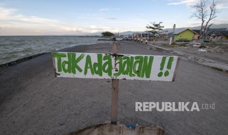 Sebuah peringatan dipasang warga di dekat pantai yang mengalami abrasi pascagempa dan tsunami di Teluk Palu, Sulawesi Tengah, Selasa (19/2/2019).