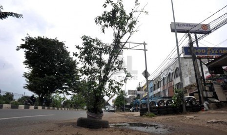 Sebuah pohon dipasang untuk menutupi lubang jalanan di jalan kalimalang, bekasi, jawa barat, Selasa (25/4).