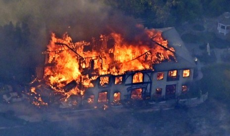 Sebuah rumah dilalap api dalam kebakaran di Kalifornia. Kebakaran hutan mungkin akan lebih sering terjadi akibat perubahan iklim.