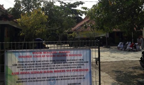 Sebuah spanduk yang menginformasikan tentang aksi mogok mengajar para guru honorer terpasang di depan gerbang SD Pabean Udik 1, Kabupaten Indramayu, Senin  (15/10). Ribuan guru honorer di Kabupaten Indramayu melakukan aksi mogok mengajar sebagai bentuk tuntutan kepada pemerintah untuk memperhatikan nasib mereka. 