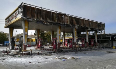 Sebuah stasiun pengisian bahan bakar hangus dibakar demonstran yang menentang kenaikan harga bahan bakar minyak (BBM) di Teheran, Iran, Ahad (17/11).