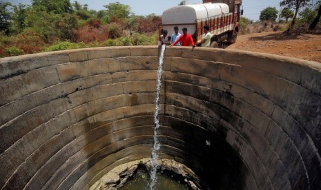 Sebuah sumur yang mengering diisi air dari truk di distrik Thane di negara bagian Maharashtra, India. India dilanda kekeringan.