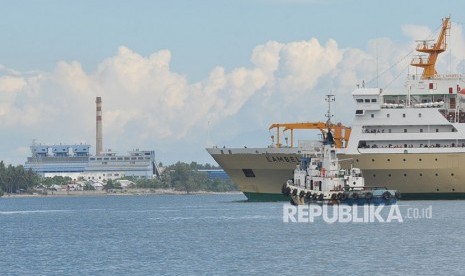 Sebuah tugboat dan kapal penumpang melintas dengan latar Pembangkit Listrik Tenaga Uap (PLTU) Mpanau di Kecamatan Tawaili, Palu Utara, Sulawesi Tengah, Sabtu (23/6).